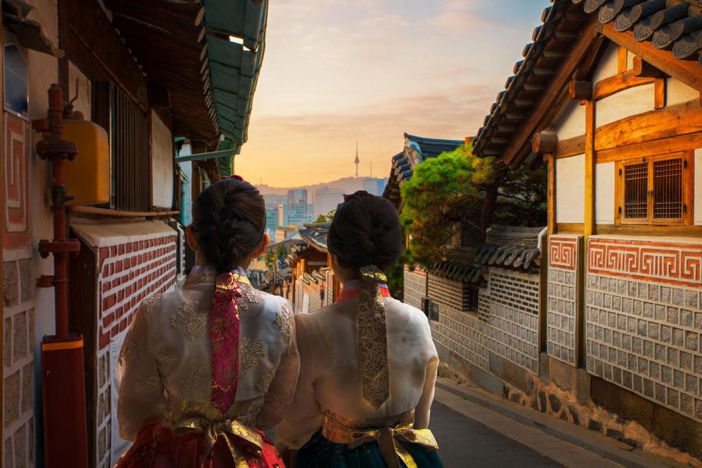 Women in hanbok walking in Bukchon Hanok Village Seoul at sunset